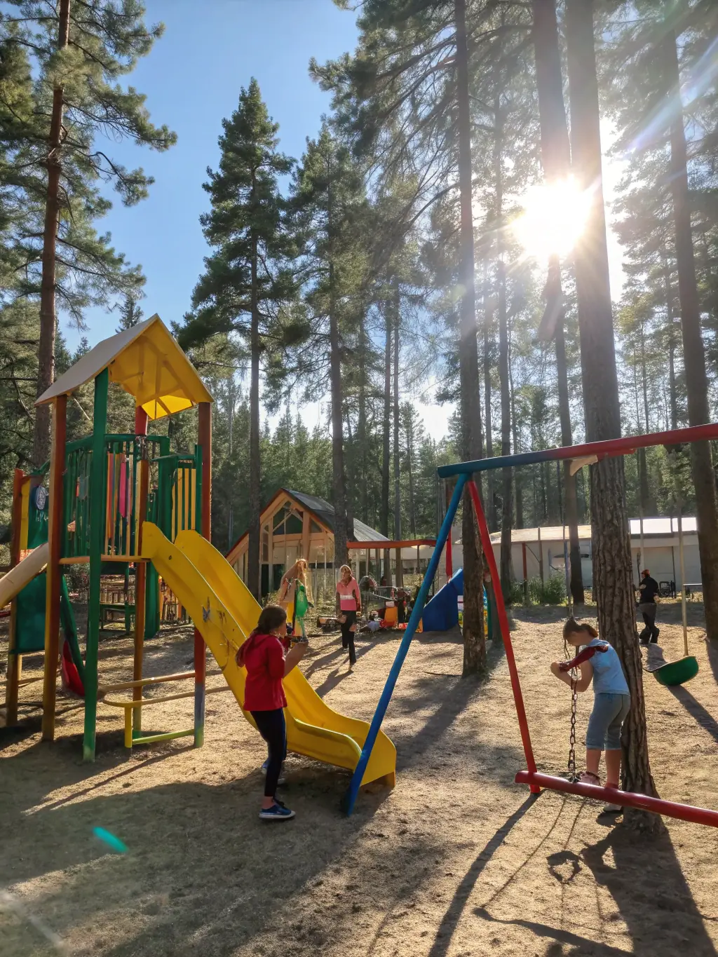 A well-equipped outdoor playground with swings, slides, and climbing structures, surrounded by lush greenery, offering children a space to play, exercise, and connect with nature at Colorful Worlds Kindergarten.