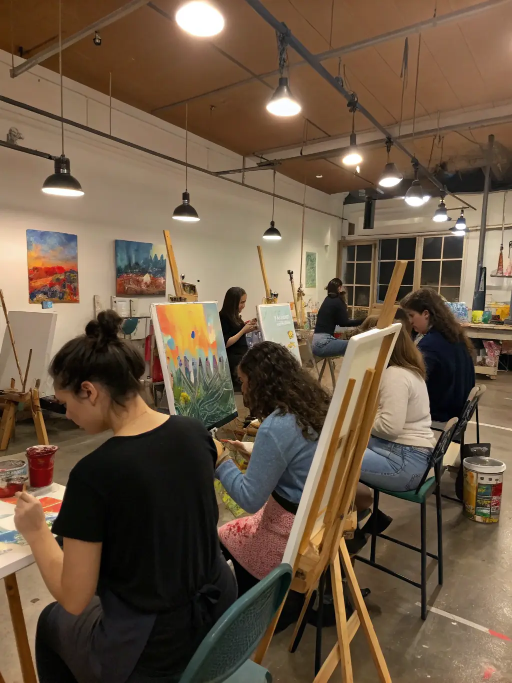 A group of 5-year-old children are working on art projects, painting and drawing at easels in a colorful art studio at Colorful Worlds, highlighting the creative and expressive opportunities available to older students.